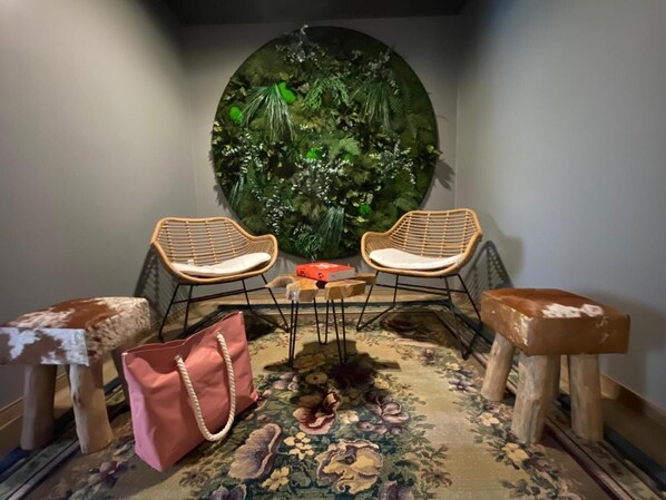 A cozy seating area with two wicker chairs, a small table, and a large decorative wall.