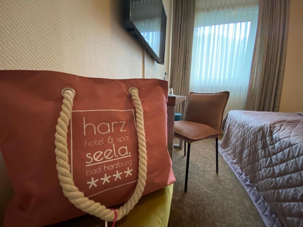 A hotel room with a bed, a chair, a desk, and a television mounted on the wall.