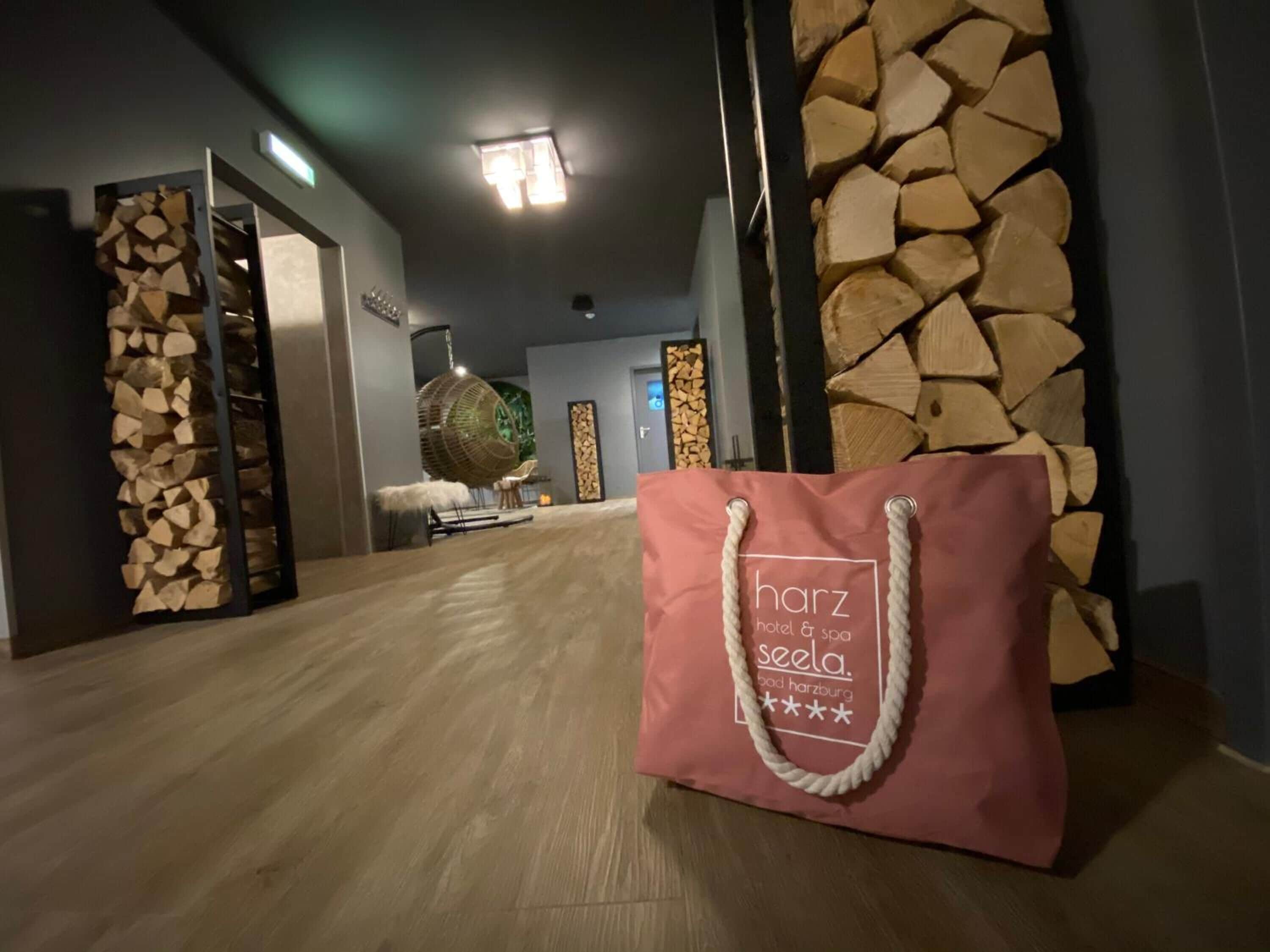Un pasillo con pared de madera y una bolsa rosa con la inscripción 'harz hotel & spa seela'.