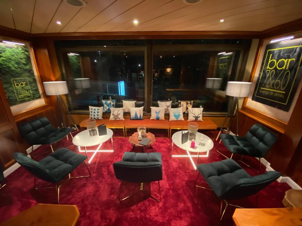 A bar/lounge area with a red carpet, modern chairs, and a large window with a view.
