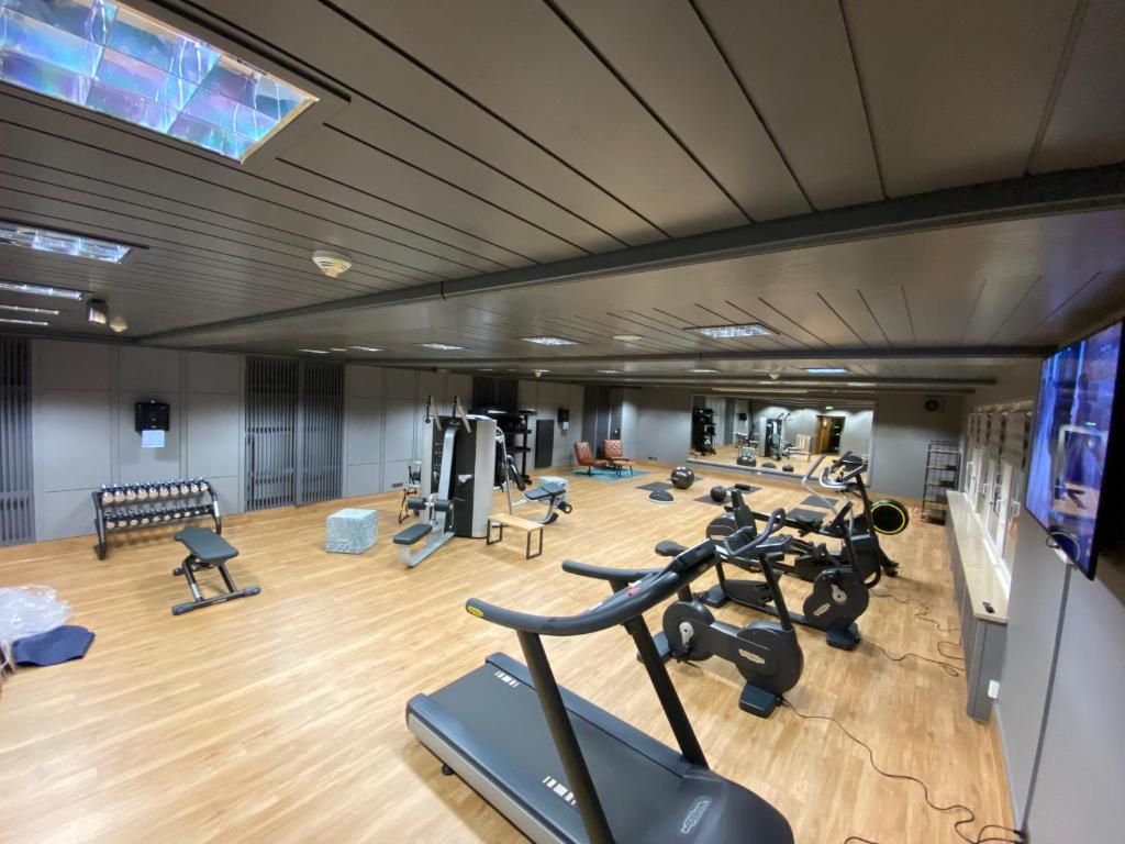 Un gimnasio con equipamiento de ejercicio, una banca y un espejo grande.