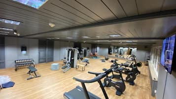 Un gimnasio con equipamiento de ejercicio, una banca y un espejo grande.