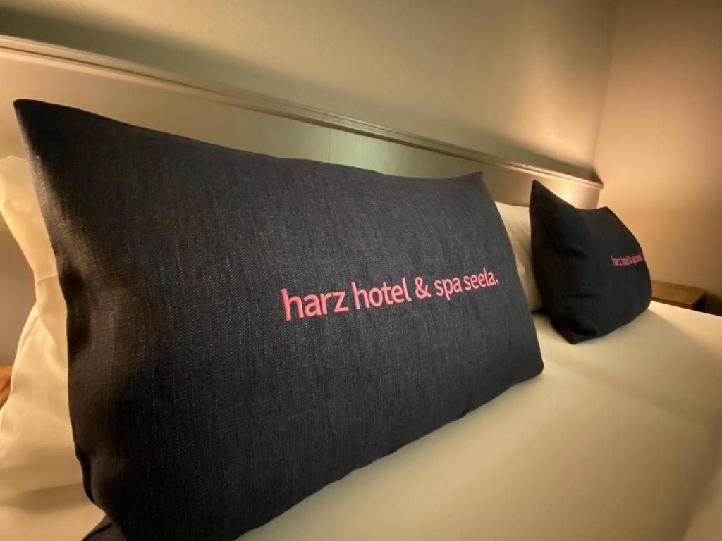 Una cama con un almohadón que muestra el texto 'harz hotel & spa seela'.