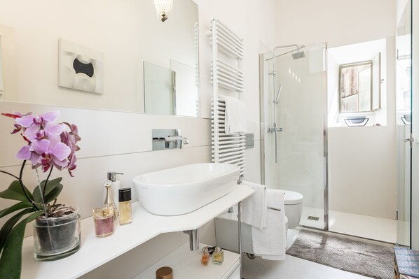 Une salle de bain moderne avec un lavabo blanc, un miroir et une douche en verre.
