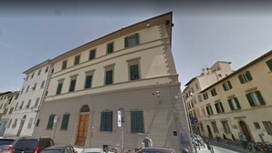 Un edificio de varios pisos con un arco de entrada destacado y una serie de ventanas con contraventanas.