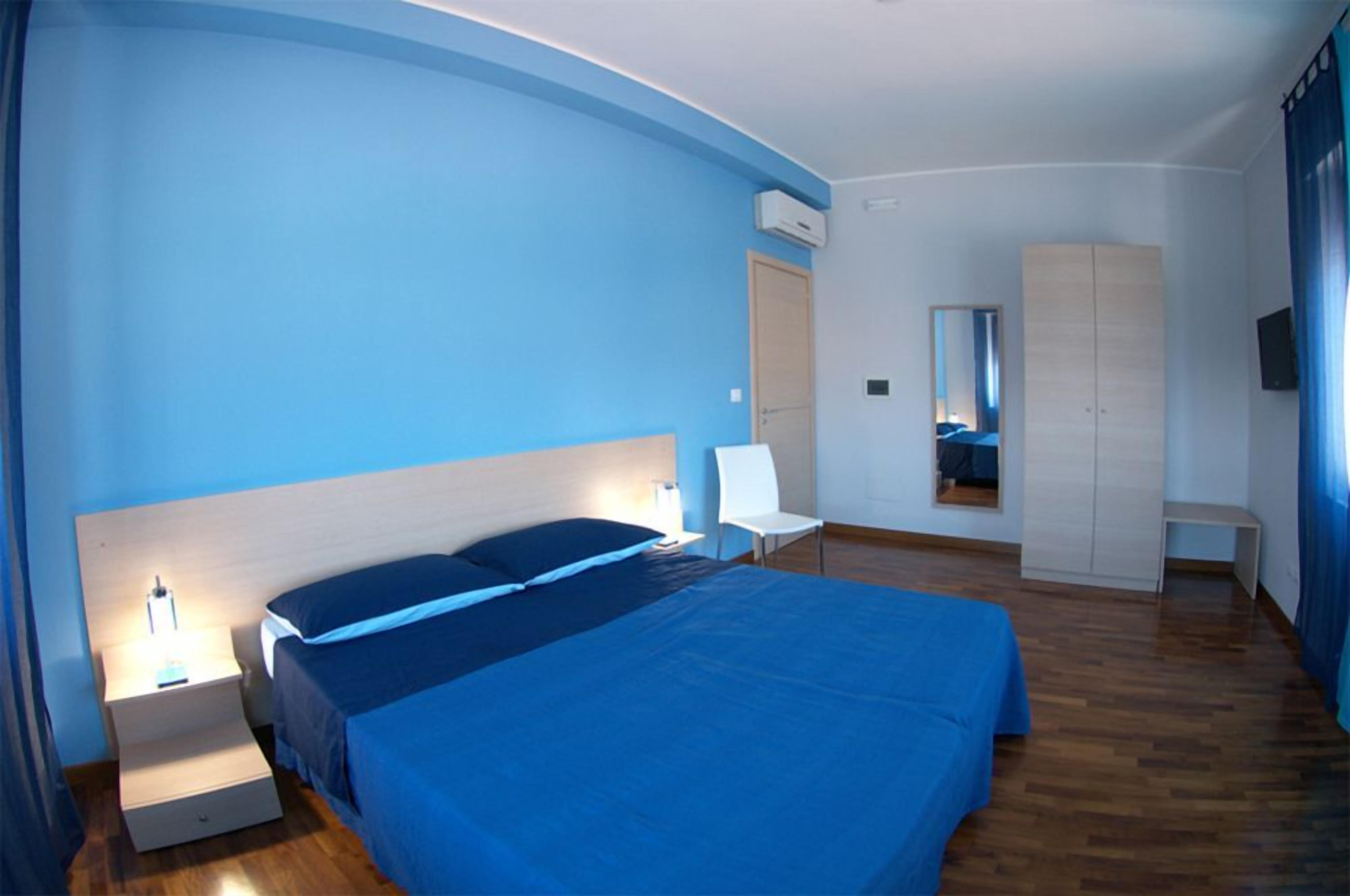 Una camera da letto con un letto grande, comodini, una sedia, un armadio e uno specchio.