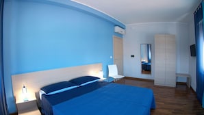 A bedroom with a large bed, bedside tables, a chair, a wardrobe, and a mirror. - B&B Santa Caterina (Reggio Calabria)