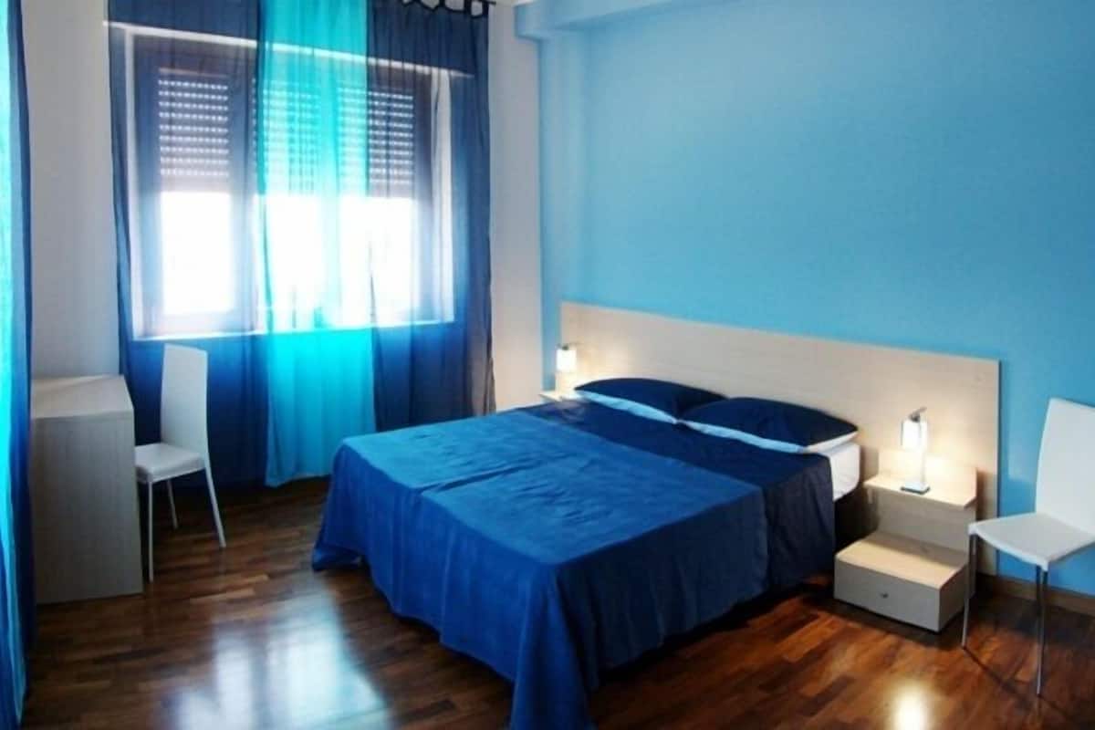 A bedroom with a bed, bedside tables, a chair, and a window with curtains.