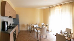 A compact kitchen with a stove, oven, and cabinets, adjacent to a dining area with multiple tables and chairs. - B&B Santa Caterina (Reggio Calabria)