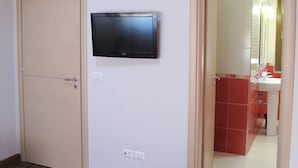 A room with a television mounted on the wall, a wooden door, and a red carpet. - B&B Santa Caterina (Reggio Calabria)