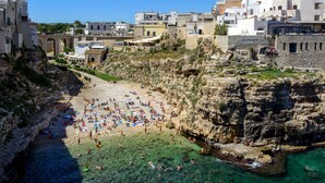 Un pueblo costero con playa rocosa, aguas cristalinas y arquitectura tradicional.