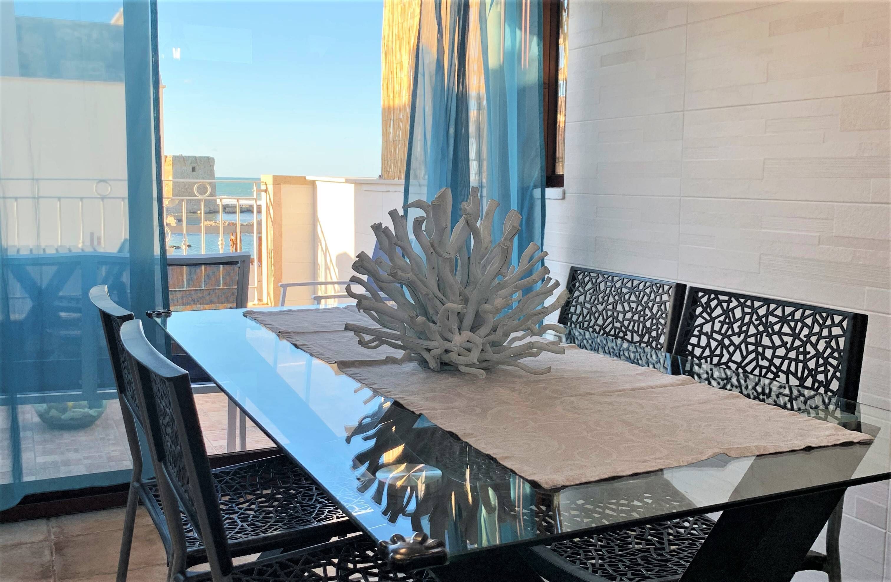 A glass-top dining table with a beige table runner and a white coral-like centerpiece.
