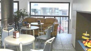 Un espacio interior moderno con sofá, mesas, sillas, un pilar grande y una exhibición de frutas.
