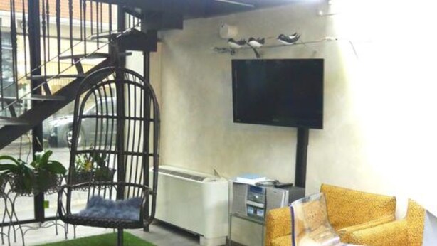 Una sala de estar moderna con una escalera, un televisor de pantalla plana y una mesa de vidrio.