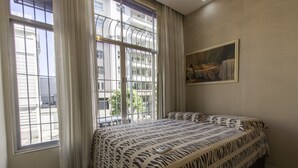 A bedroom with a large window, a zebra-patterned bed, and a painting on the wall. - LineRio Copacabana Luxury Residence 161 (Rio de Janeiro)