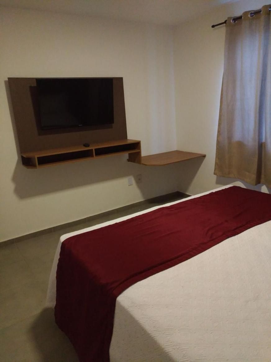 Ein Zimmer mit einem Bett, einem an der Wand montierten Fernseher, einem Regal und einem Vorhang.