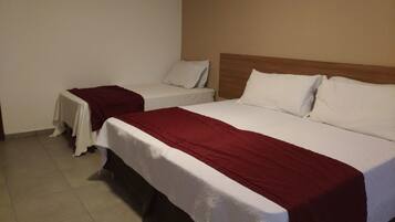 Quarto de hotel com duas camas de solteiro, cada uma com roupa de cama branca e um cobertor vermelho.