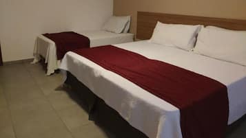 Ein Hotelzimmer mit zwei Einzelbetten, jeweils mit einer weißen Matratze und einer roten Decke.