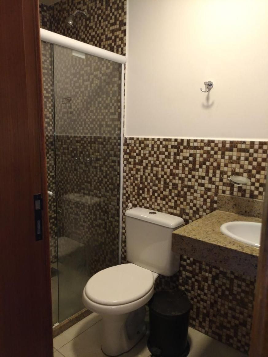A bathroom with a toilet, shower, and sink.