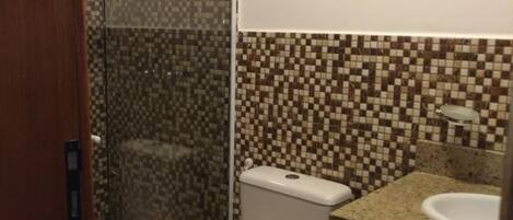 A bathroom with a toilet, shower, and sink.