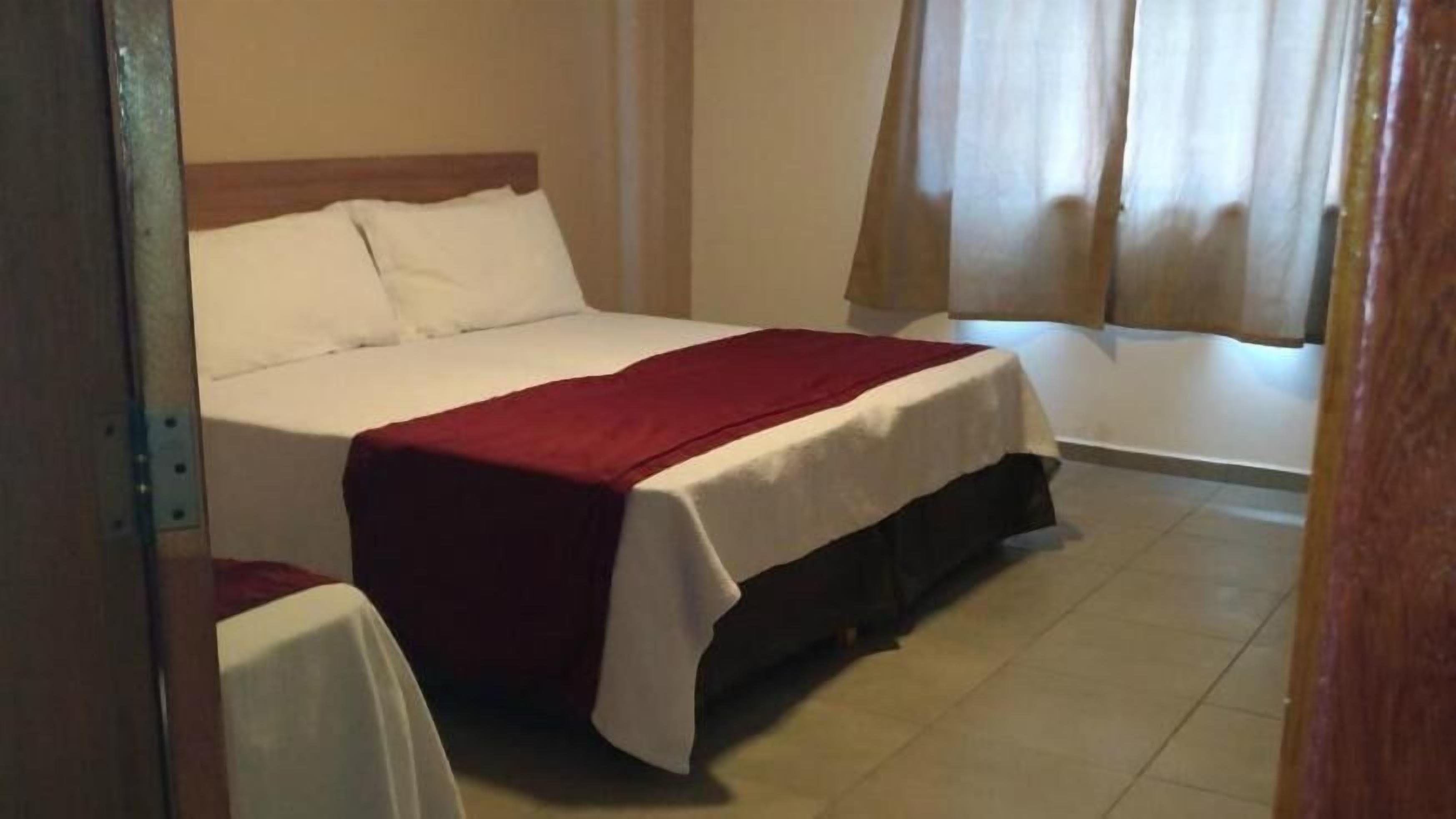 Ein Schlafzimmer mit einem Bett, einer roten Decke und einem weißen Tisch.