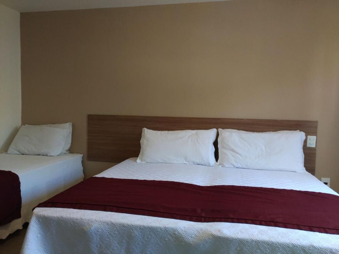 Ein Hotelzimmer mit einem großen Bett, zwei weißen Kissen, einem hölzernen Kopfteil und einer roten Decke.