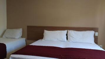 Ein Hotelzimmer mit einem großen Bett, zwei weißen Kissen, einem hölzernen Kopfteil und einer roten Decke.