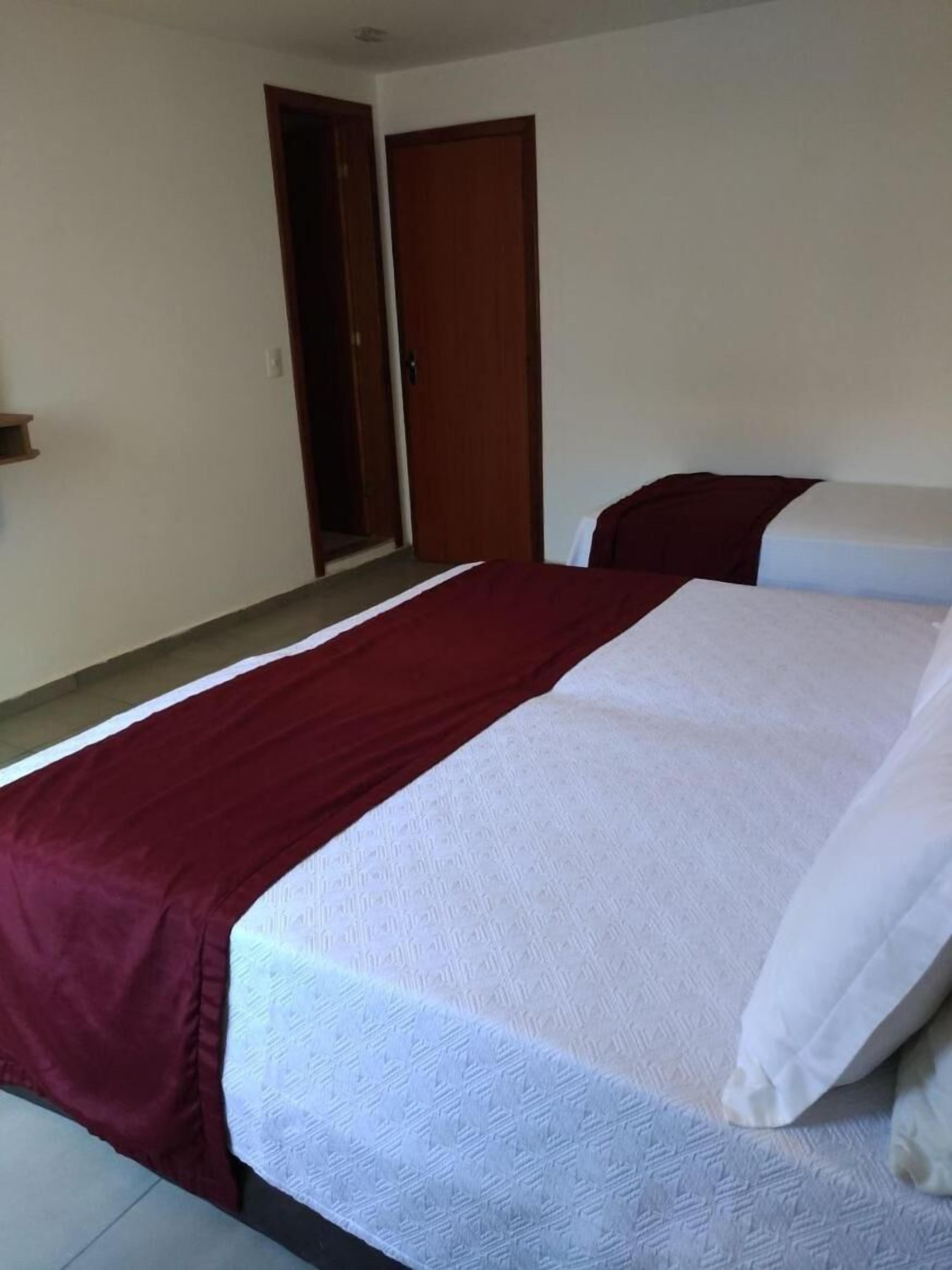Ein Schlafzimmer mit einem Bett, einer Holztür und einem kleinen Regal.