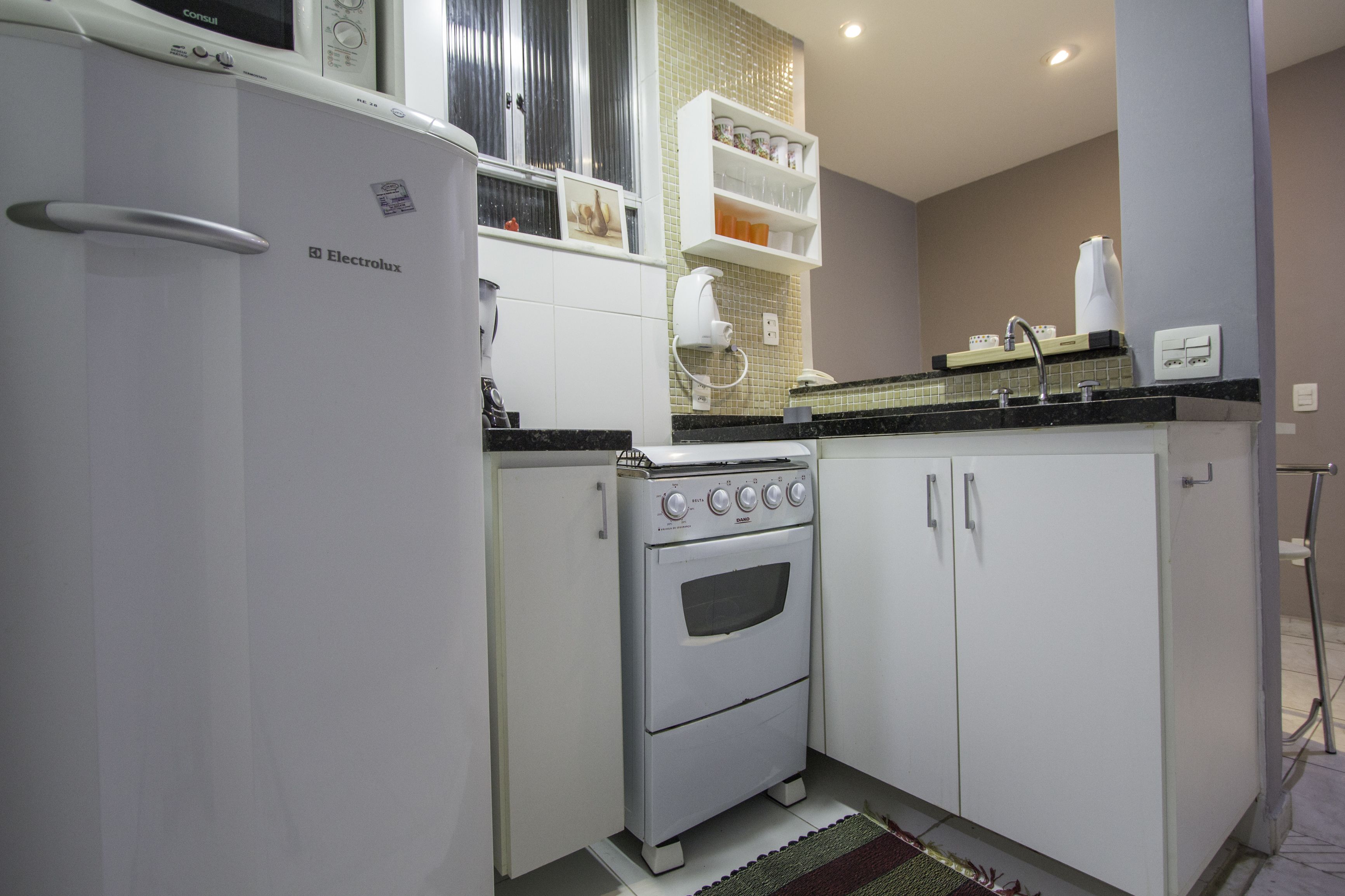 Een compacte keuken met witte kasten, een ingebouwde oven en een magnetron.
