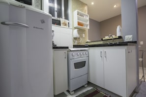 A compact kitchen with white cabinetry, a built-in oven, and a microwave.