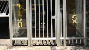 Um portão de metal com o número 150, que dá acesso a um edifício com uma placa que diz 'Edificio Dom Carlos'.