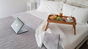 A neatly made bed with a laptop, a tray with breakfast, and a welcome sign. - Terry's House (Nuoro)