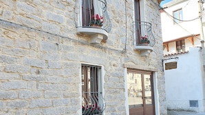 A stone building with two balconies, each with metal railings and potted plants. - Terry's House (Nuoro)