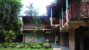 A two-story building with a balcony, surrounded by lush greenery and palm trees. - Hareesha Holiday Resort (Yakkalamulla)