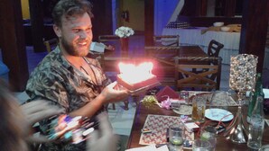 A man holding a lit candle, a dining table with plates, glasses, and a bottle. - Hareesha Holiday Resort (Yakkalamulla)