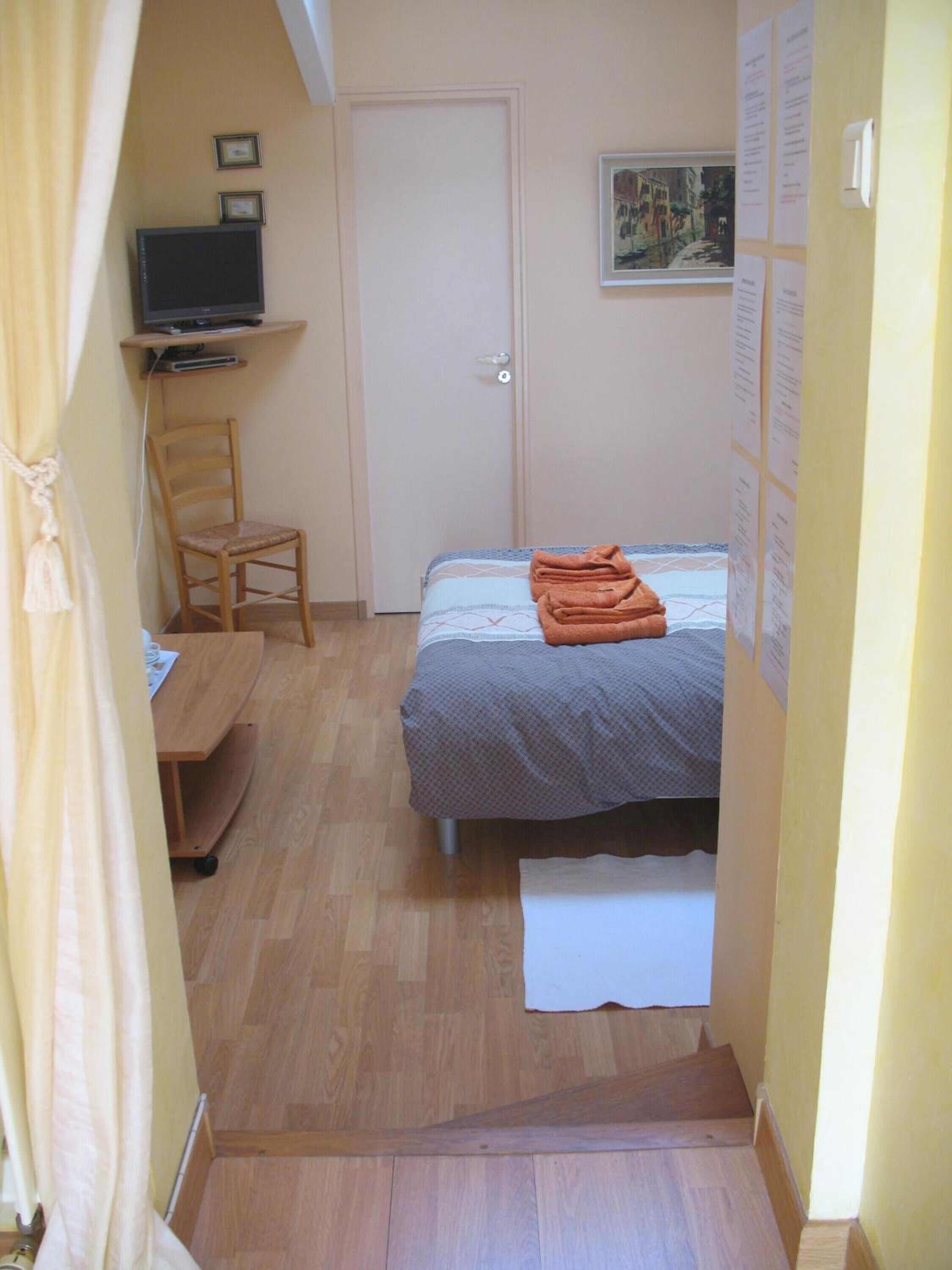 A bedroom with a bed, a chair, a desk, and a television.