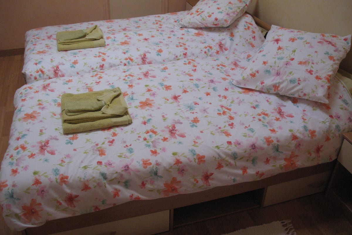 A bed with floral bedding and two folded towels.