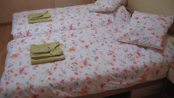 Een bed met bloemenbedrukking en twee opgevouwen handdoeken.
