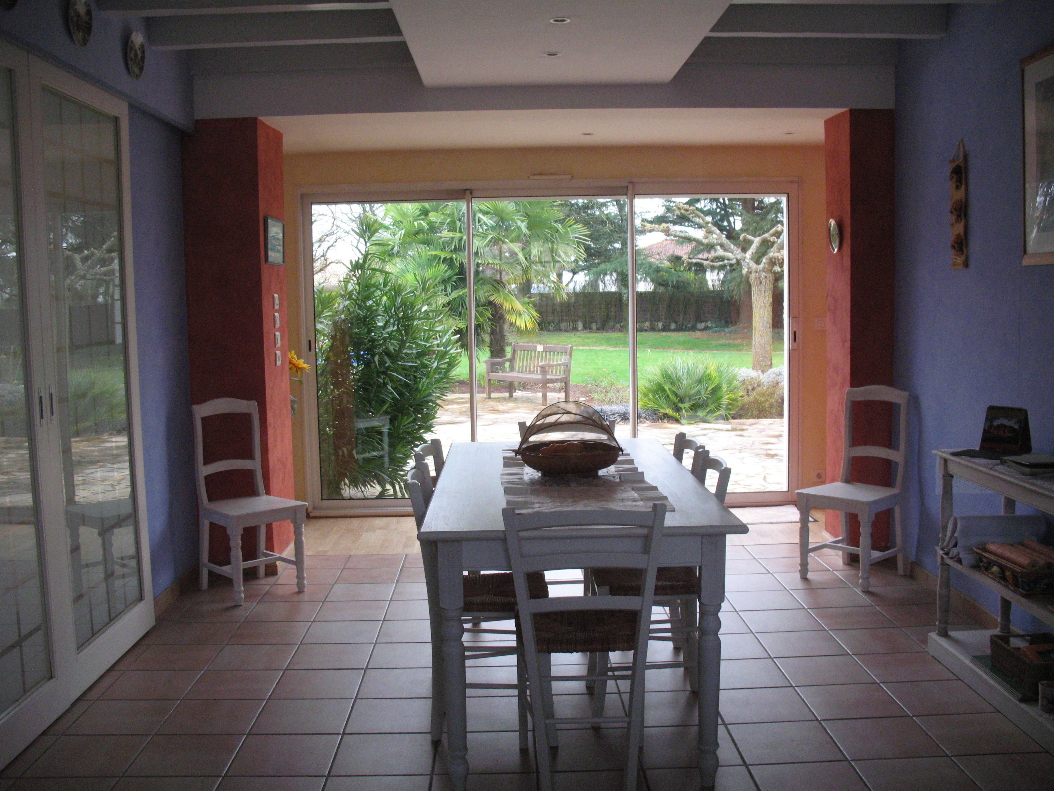 A dining area with a table and chairs, a sliding glass door leading to a garden.