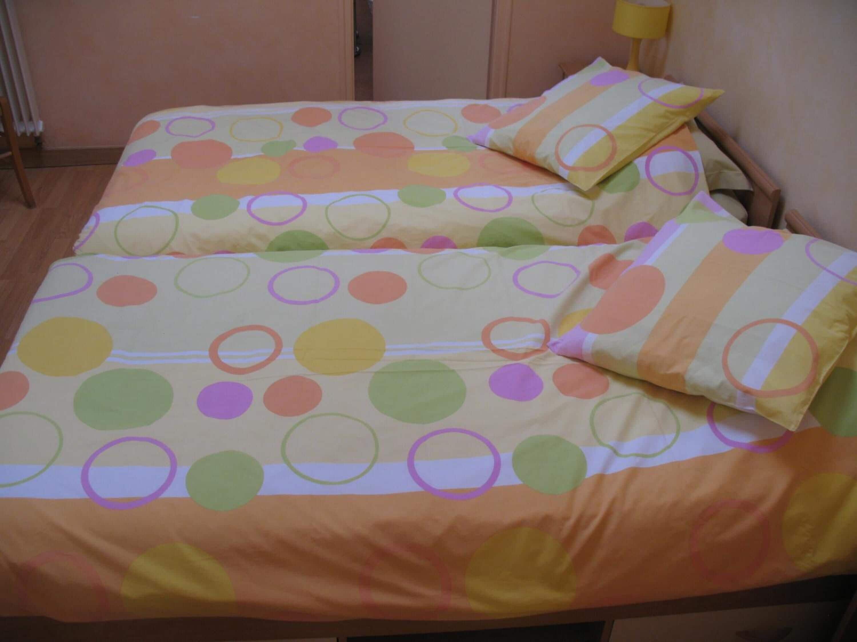 A bed with a polka dot bedspread and matching pillows.