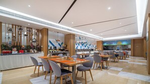 A modern dining area with multiple tables and chairs, a counter with various items, and a wall with decorative elements. - Holiday Inn Express Chengdu Tianhe by IHG (Chengdu)