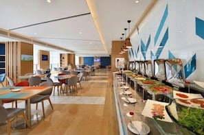 A modern hotel dining area with multiple tables and chairs, a buffet line with various food options, and a decorative wall with geometric patterns. - Holiday Inn Express Chengdu Tianhe by IHG (Chengdu)