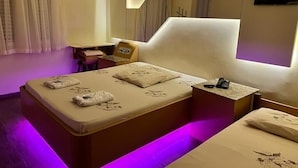 A hotel room with a large bed, bedside tables, a chair, and a TV.