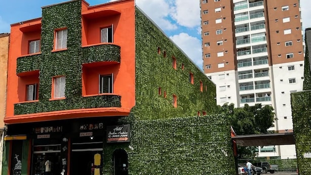 A building with a green ivy-covered facade and a red and orange storefront.