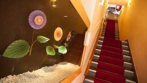 A staircase with a red carpet, a glass enclosure with decorative paper flowers, and a pebbled floor.