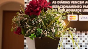 A reception desk with a potted plant of red flowers and a menu board in the background.