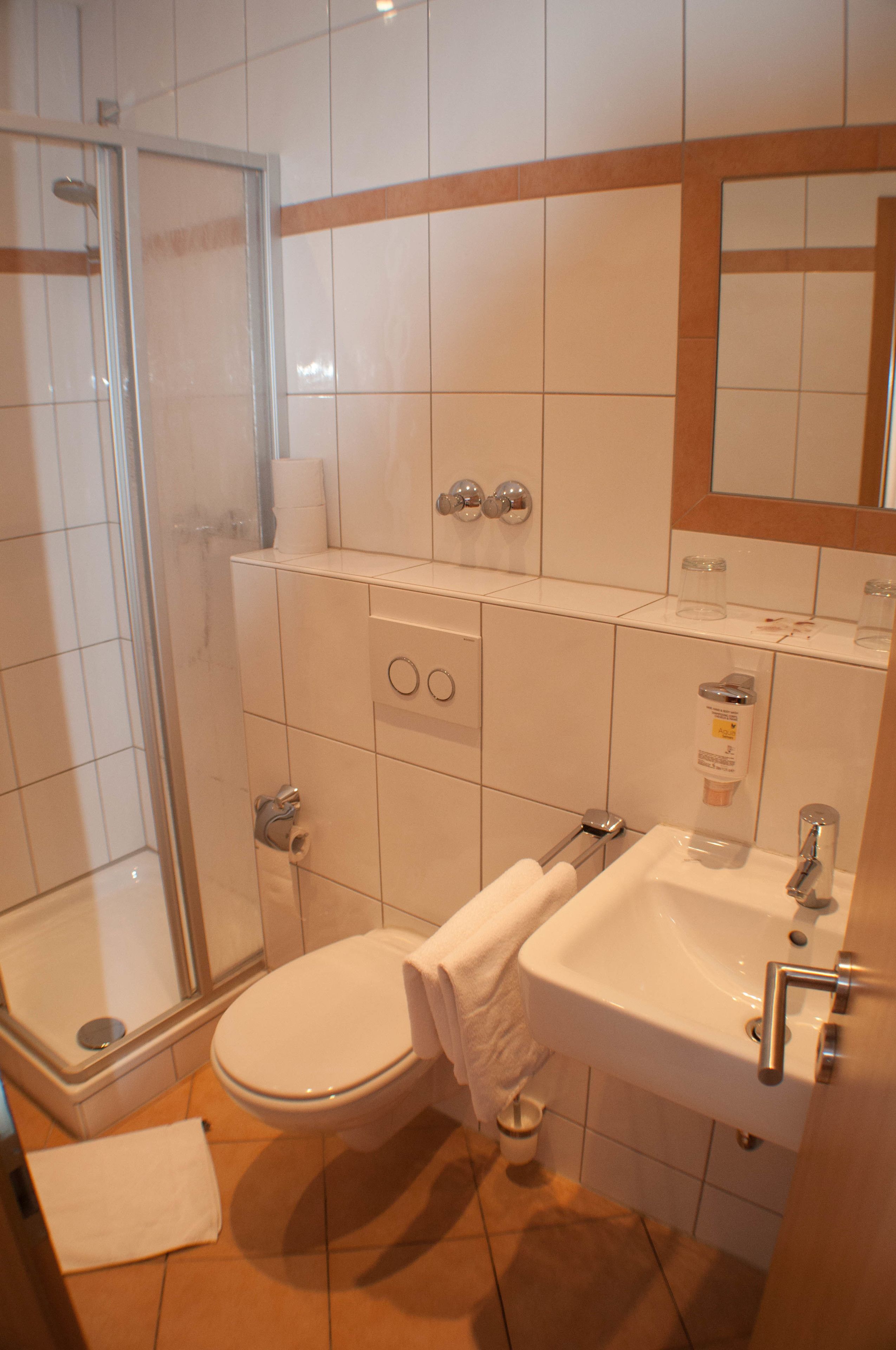 Un baño con ducha, inodoro, lavamanos y espejo.
