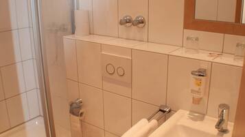 Un baño con ducha, inodoro, lavamanos y espejo.