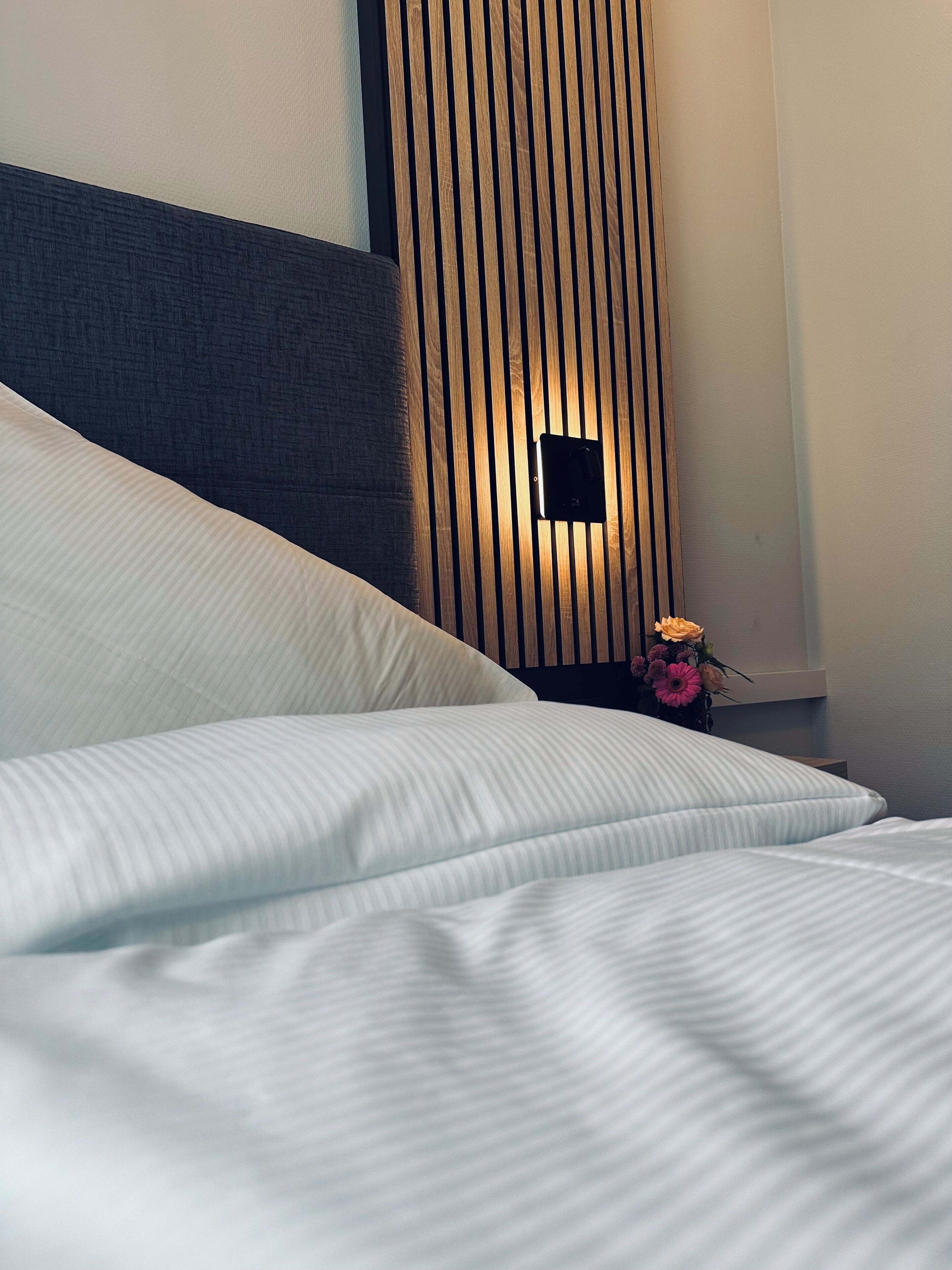 Una cama bien hecha con sábanas blancas y un cabecero de madera.