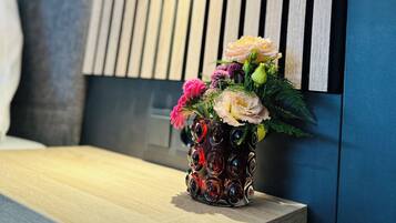 Um banco de madeira com um vaso de flores em frente a uma parede com ripas de madeira verticais e uma pequena moldura.